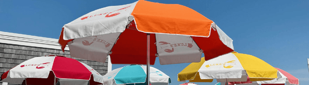 Commercial patio umbrellas with custom printed logos and vibrant canopy colors, designed for branded outdoor spaces at restaurants, resorts, and beachfront venues.